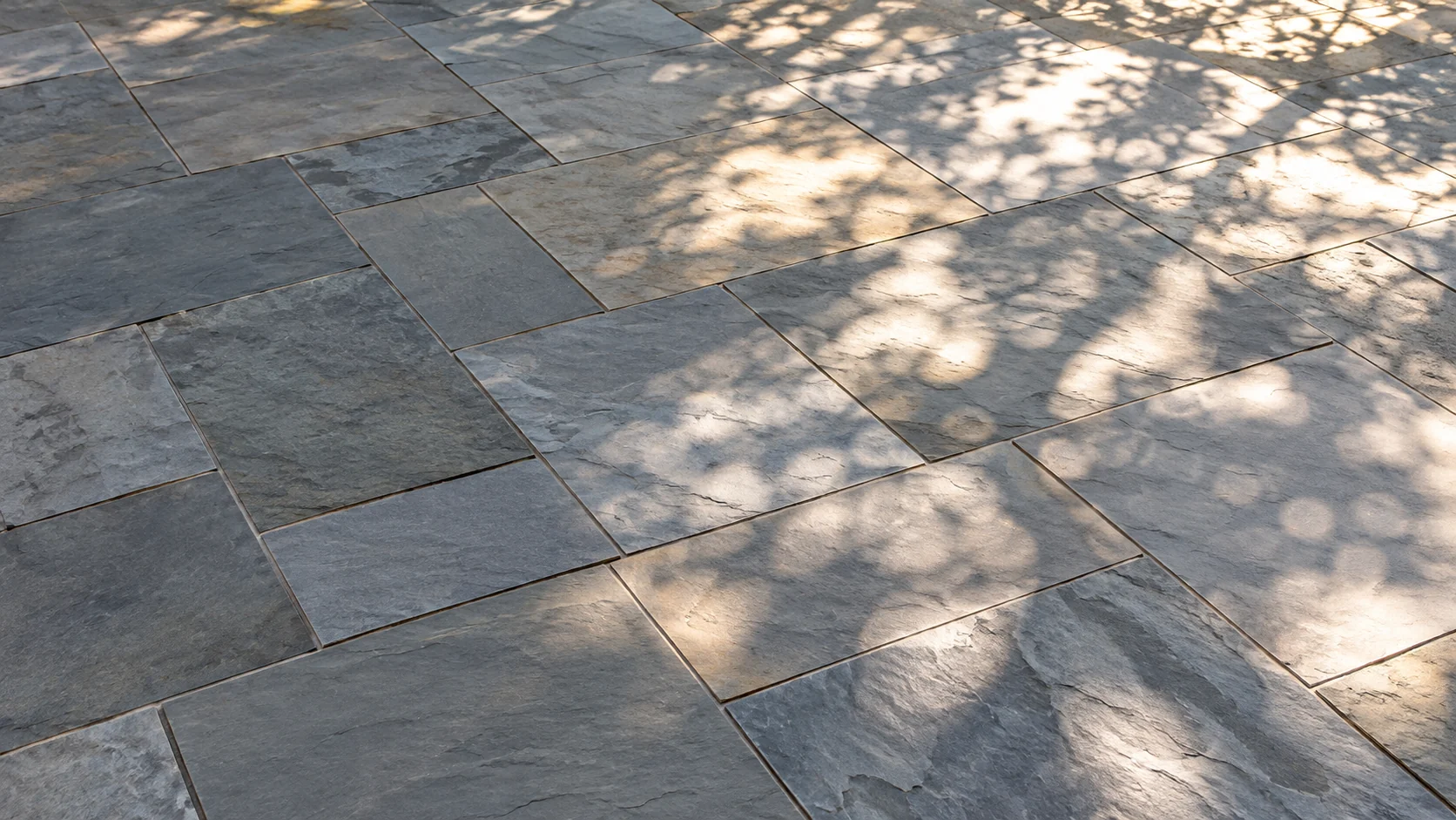 Dappled sunlight and leaf shadows on freshly laid natural bluestone paving
