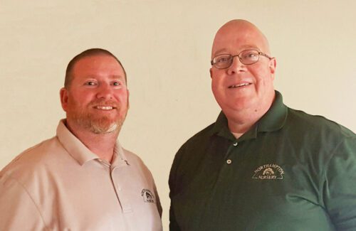 Two men smiling, one wearing a green shirt.